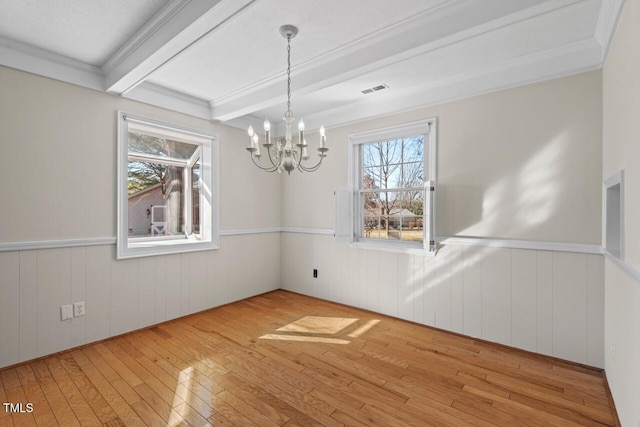 unfurnished dining area with light wood finished floors, beamed ceiling, wainscoting, and visible vents