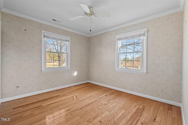 empty room featuring light wood-type flooring, plenty of natural light, visible vents, and ornamental molding