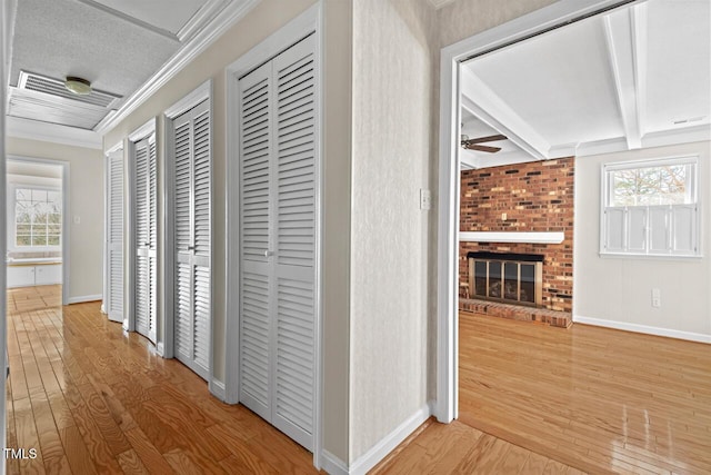 hallway with ornamental molding, beamed ceiling, plenty of natural light, and wood finished floors