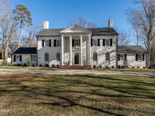 neoclassical / greek revival house featuring a chimney and a front yard