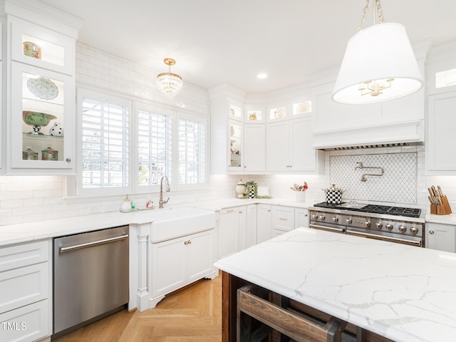 kitchen with glass insert cabinets, appliances with stainless steel finishes, white cabinetry, pendant lighting, and a sink