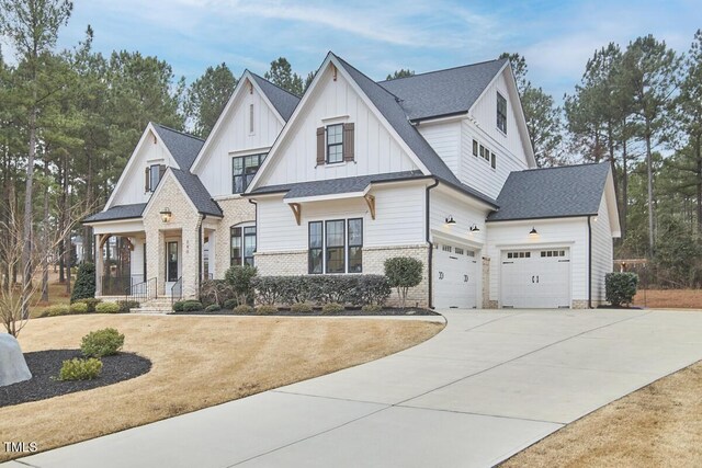 modern inspired farmhouse featuring an attached garage, brick siding, driveway, roof with shingles, and board and batten siding