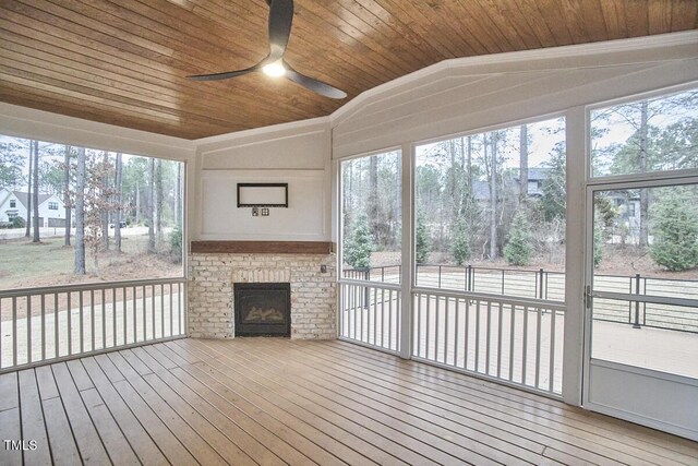 unfurnished sunroom featuring wood ceiling, a fireplace, vaulted ceiling, and a wealth of natural light