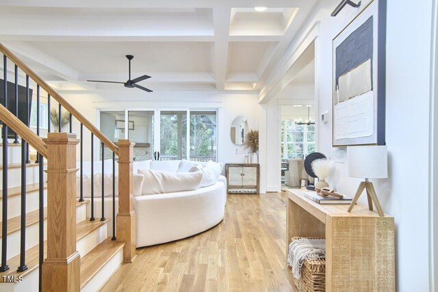 living area with stairway, light wood-style floors, ceiling fan, coffered ceiling, and beamed ceiling