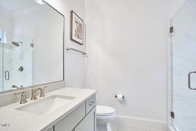 full bath featuring toilet, a shower stall, vanity, and baseboards