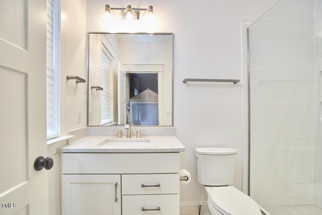 bathroom with a tile shower, vanity, and toilet