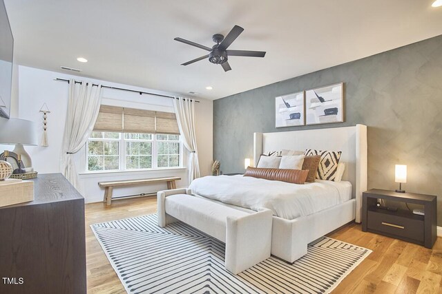 bedroom featuring an accent wall, recessed lighting, a ceiling fan, and light wood-style floors