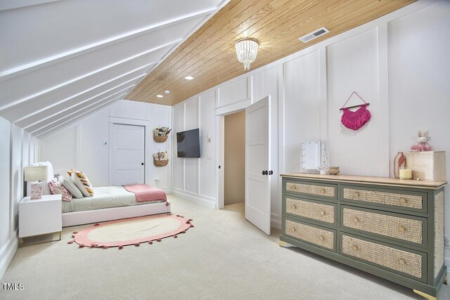 bedroom featuring light carpet, lofted ceiling, visible vents, and a decorative wall