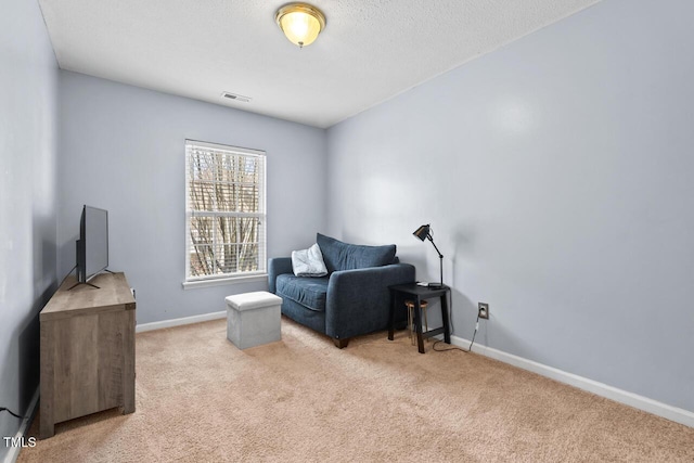 sitting room featuring light carpet, visible vents, baseboards, and a textured ceiling