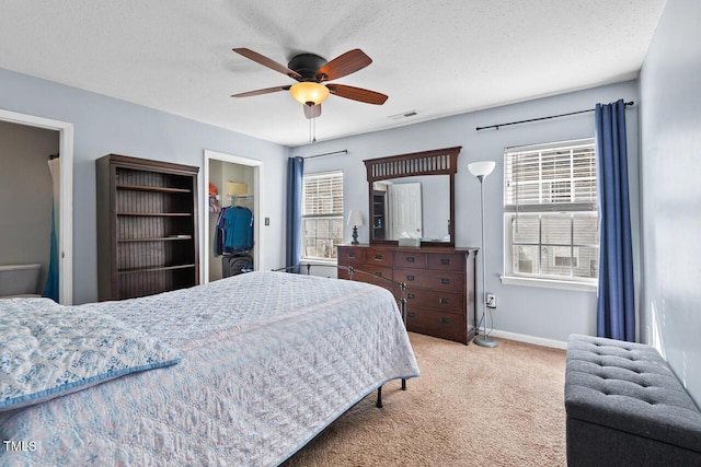 carpeted bedroom with baseboards, visible vents, a walk in closet, a textured ceiling, and a closet