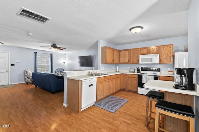 kitchen featuring light countertops, visible vents, open floor plan, white appliances, and a peninsula