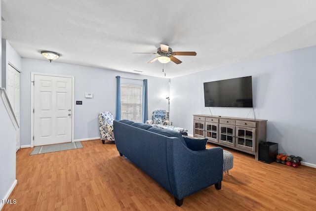 living room with light wood-type flooring, baseboards, and a ceiling fan