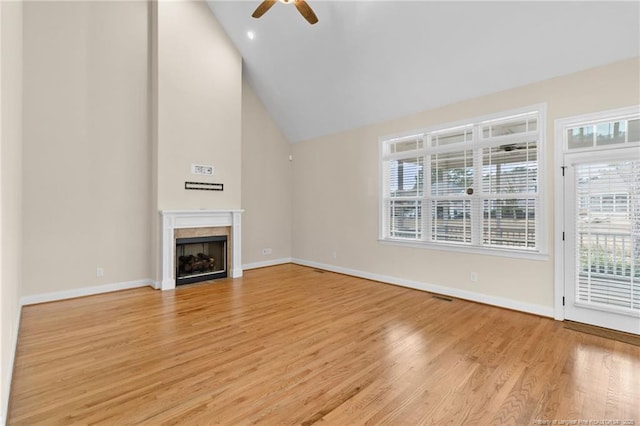 unfurnished living room featuring high vaulted ceiling, a fireplace, a ceiling fan, baseboards, and light wood-type flooring