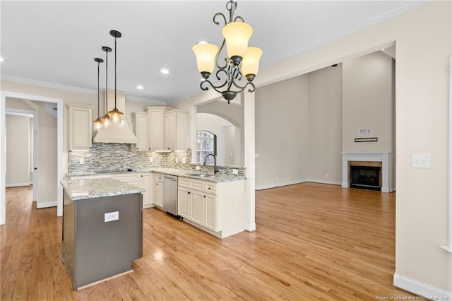 kitchen featuring hanging light fixtures, a sink, light stone counters, and stainless steel dishwasher