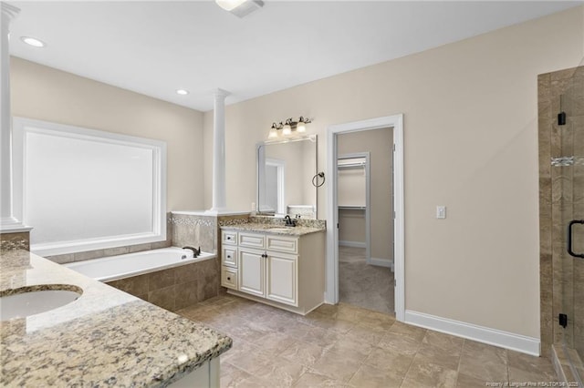 bathroom with a shower stall, a spacious closet, a sink, and ornate columns