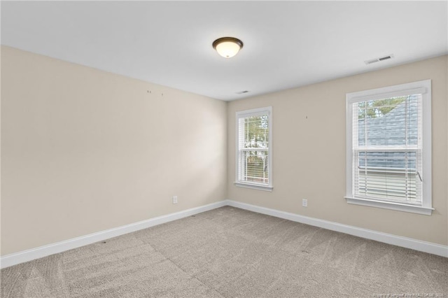 carpeted spare room with visible vents and baseboards