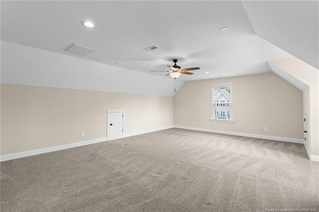 additional living space featuring visible vents, a ceiling fan, light carpet, vaulted ceiling, and baseboards