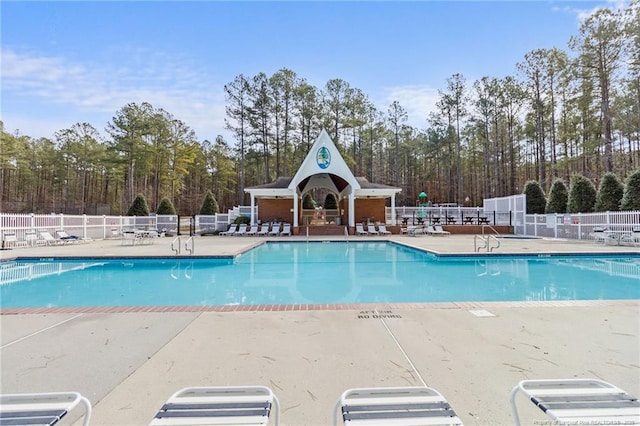 community pool with a patio area and fence