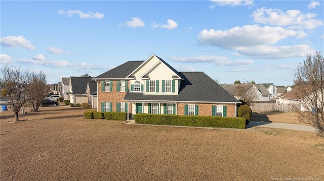 view of front of home featuring brick siding, fence, and a residential view