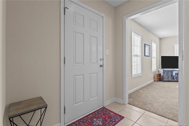 entrance foyer featuring light carpet, light tile patterned flooring, and baseboards