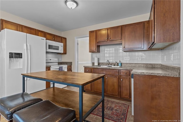 kitchen with tasteful backsplash, white appliances, brown cabinets, and a sink