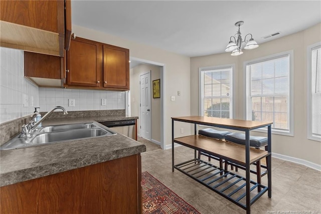 kitchen with visible vents, decorative backsplash, dark countertops, decorative light fixtures, and a sink