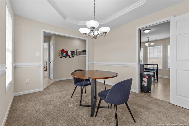 dining space featuring a raised ceiling, light colored carpet, an inviting chandelier, ornamental molding, and baseboards