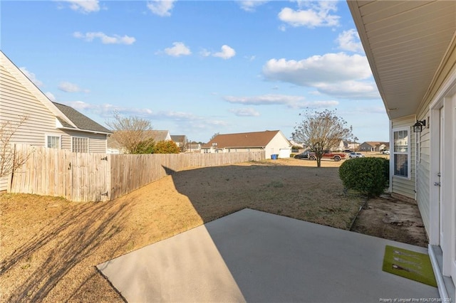 view of yard with a patio area, fence, and a residential view