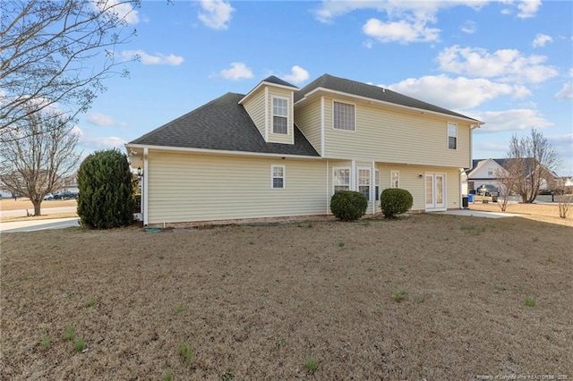 back of house with a shingled roof and a yard