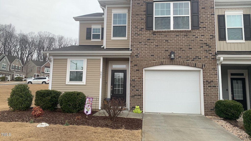 view of front of house with a garage, board and batten siding, concrete driveway, and brick siding