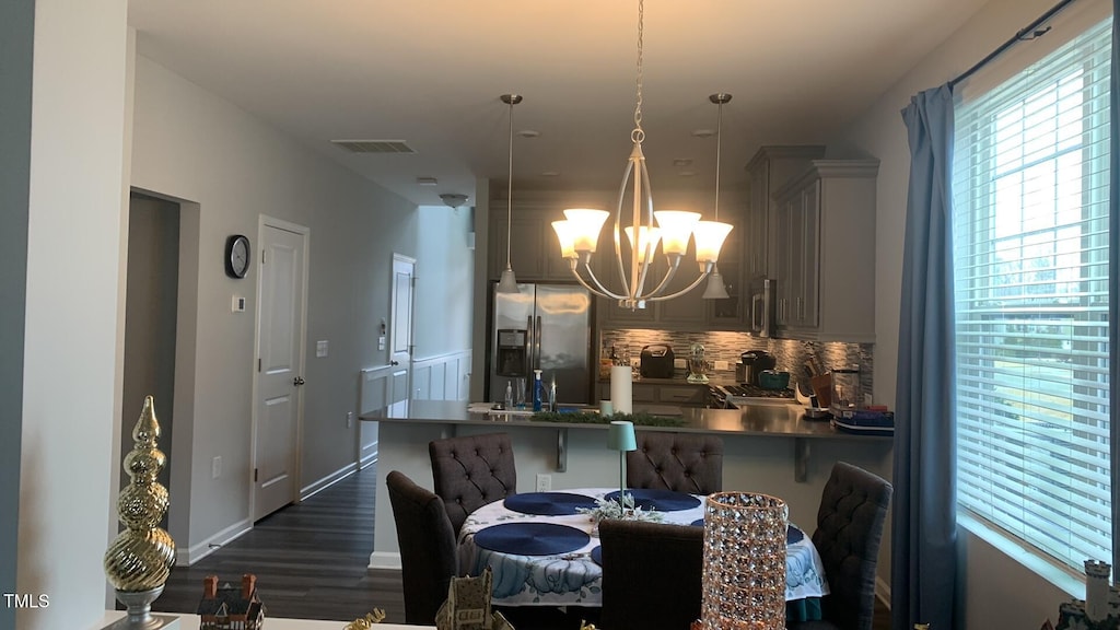 dining space with a chandelier, baseboards, visible vents, and dark wood-type flooring