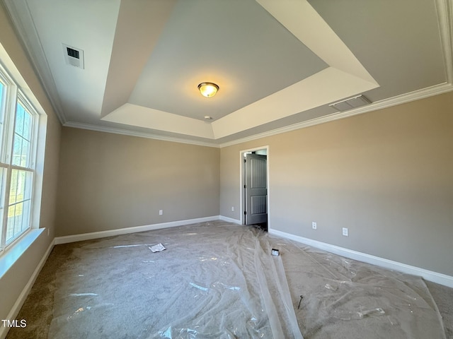 spare room with ornamental molding, a tray ceiling, visible vents, and baseboards