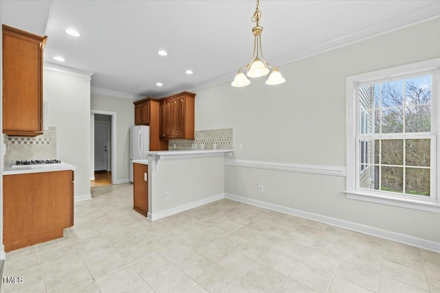 kitchen featuring brown cabinetry, decorative light fixtures, a peninsula, light countertops, and crown molding