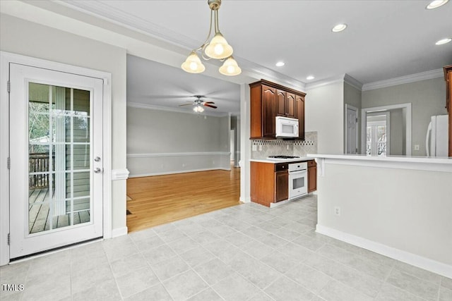 kitchen with white appliances, decorative light fixtures, light countertops, crown molding, and a healthy amount of sunlight