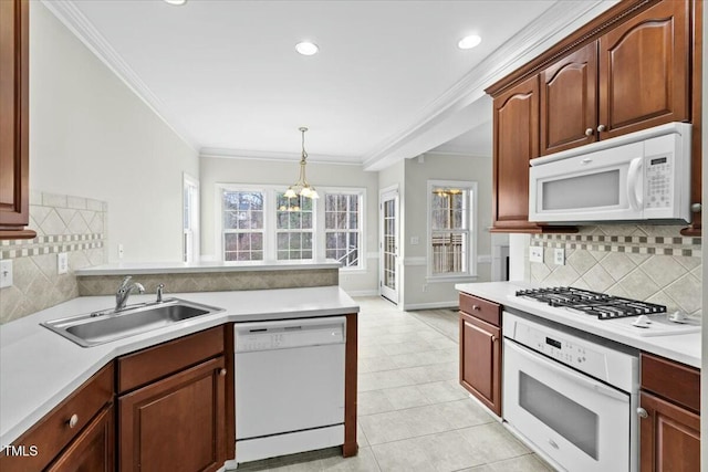 kitchen featuring hanging light fixtures, white appliances, light countertops, and a sink