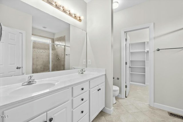 bathroom with tile patterned flooring, toilet, a sink, double vanity, and a stall shower