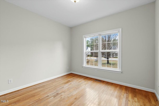 spare room featuring light wood-type flooring, visible vents, and baseboards