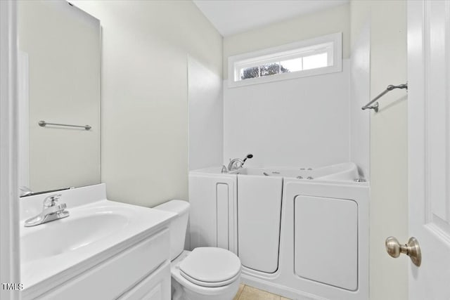 full bathroom with toilet, a bath, and vanity