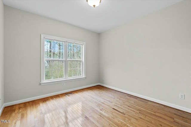 unfurnished room with visible vents, light wood-style flooring, and baseboards