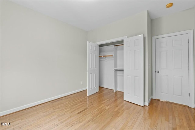 unfurnished bedroom featuring light wood-type flooring, baseboards, and a closet