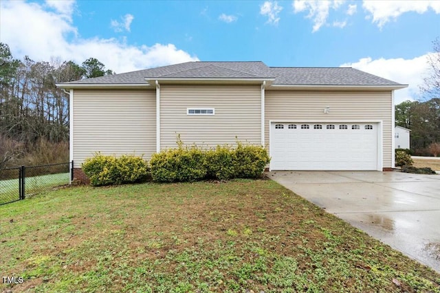 view of side of home with driveway, a garage, a shingled roof, fence, and a yard