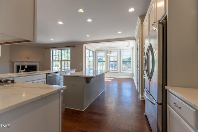 kitchen with a sink, crown molding, stainless steel appliances, white cabinetry, and dark wood-style flooring