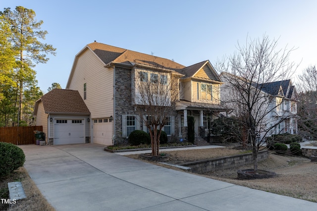 view of front of home featuring fence, stone siding, and driveway