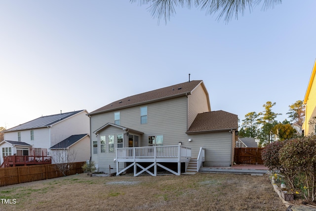 back of house featuring a wooden deck, a yard, and a fenced backyard