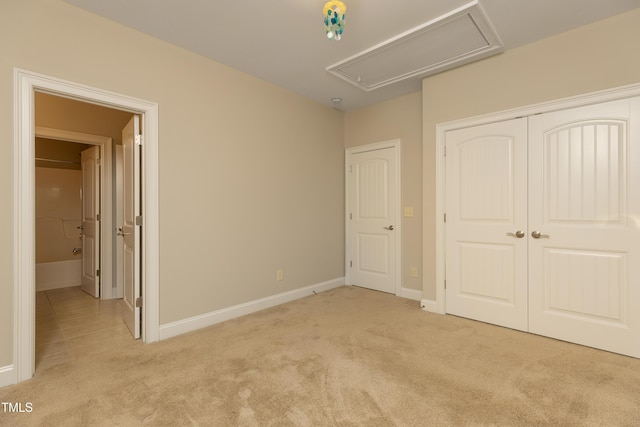 unfurnished bedroom with a closet, light carpet, baseboards, and attic access