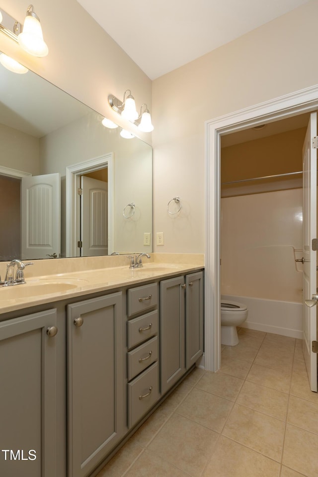 bathroom with tile patterned floors, double vanity, toilet, and a sink