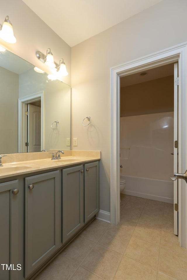 bathroom with a sink, toilet, double vanity, and tile patterned floors