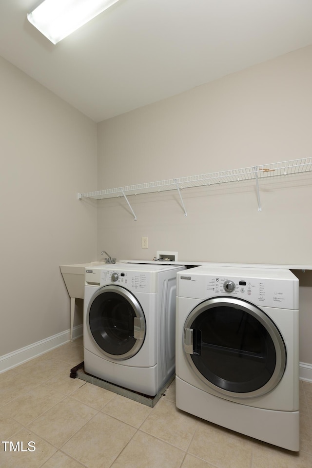 clothes washing area with light tile patterned floors, laundry area, baseboards, and separate washer and dryer