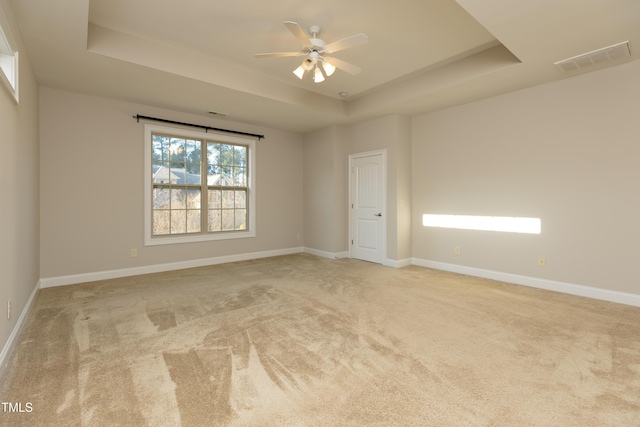 empty room featuring visible vents, baseboards, ceiling fan, carpet flooring, and a raised ceiling