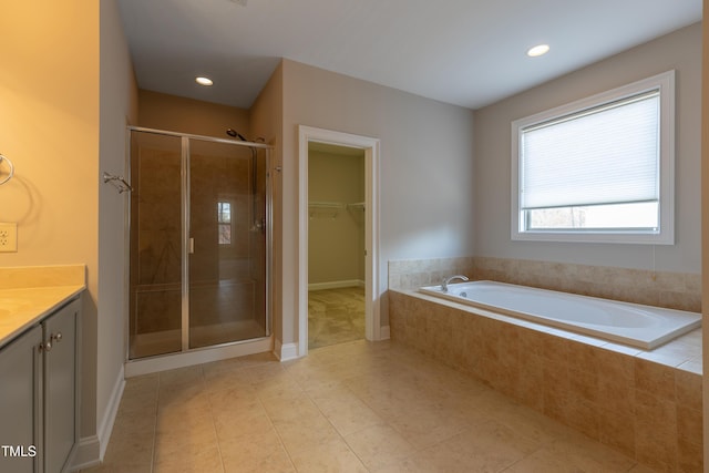 bathroom featuring vanity, tile patterned flooring, a shower stall, a walk in closet, and a bath